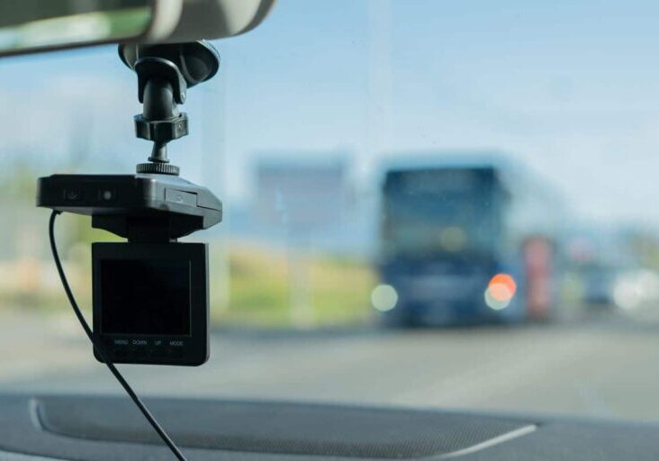 A car camera is mounted on the dashboard of a vehicle.